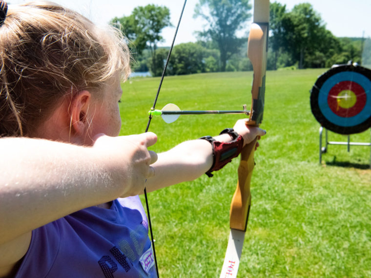 Girl with a bow and arrow on the archery field ready to shoot