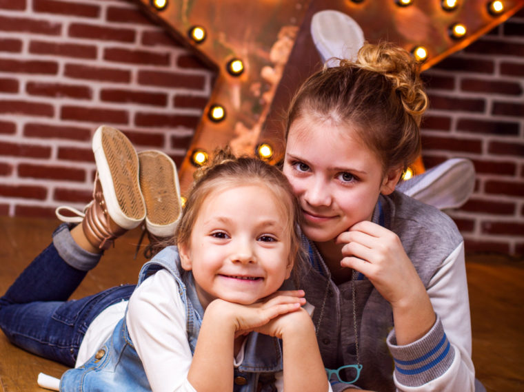 Two girls on their stomachs with legs up in the air behind them and hands under their chins