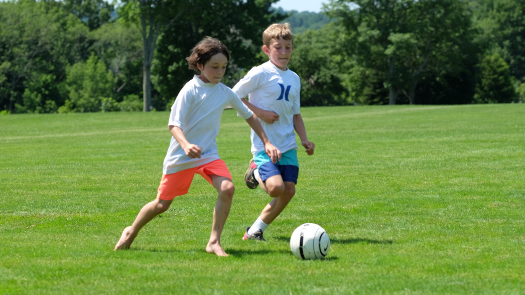 Two campers playing soccer on a field