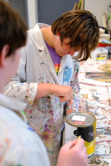 Boy in an art smock that is covered in paint.
